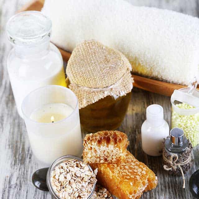 Candles, honey, lotion, white towel and oats ingredients for a homemade beauty