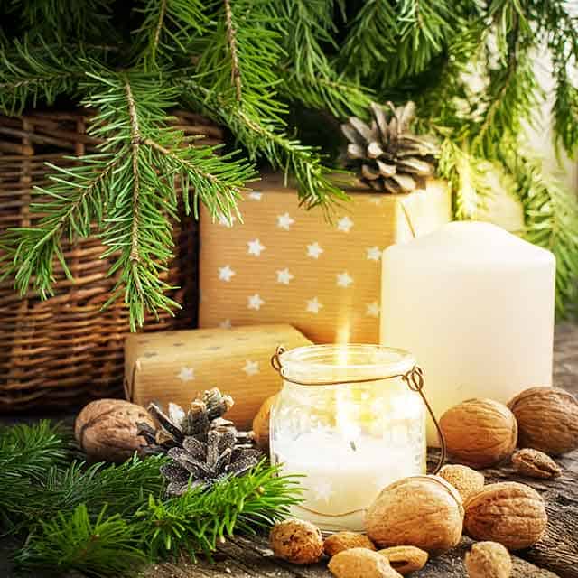 Candles, almonds, and present underneath a pine tree