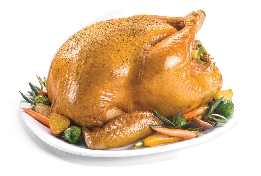 Whole, natural turkey on a platter with various vegetables
