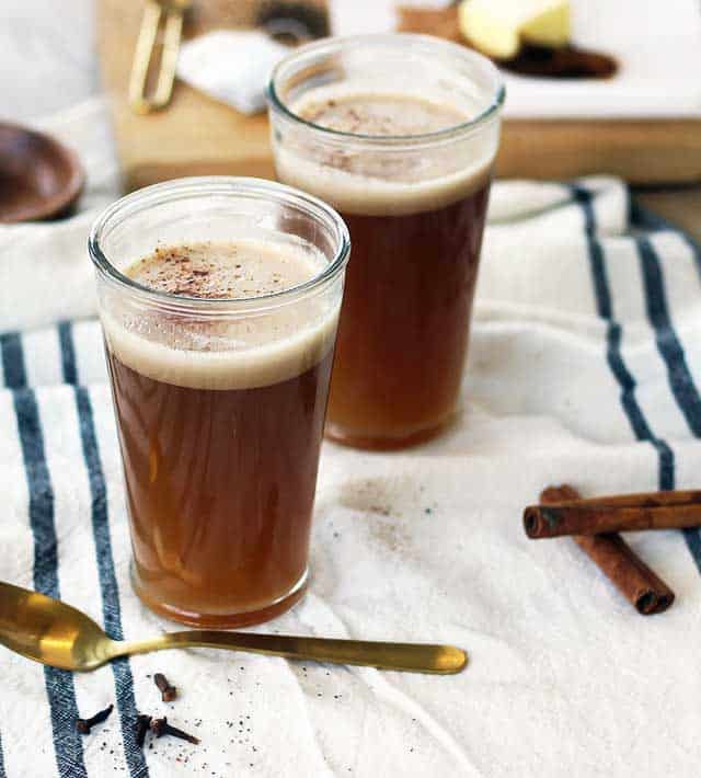 Two glasses of Chai Latte with cinnamon sticks & spoon on the side