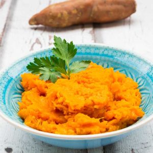 sweet potato hummus in blue bowl with sweet potato in background