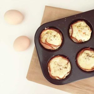 ham and egg cups in a muffin tin with two eggs on the side