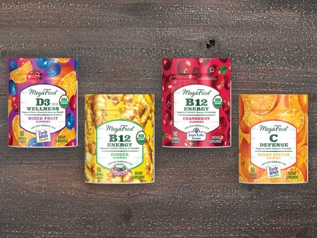 Four bottles of MegaFood gummies in a row on a wood background