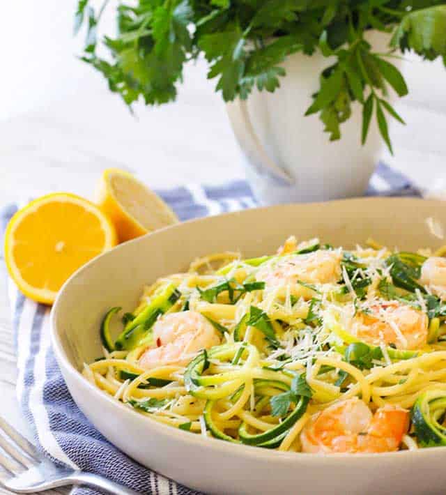 Bowl of Shrimp Scampi Zoodles with halved orange on side and plant