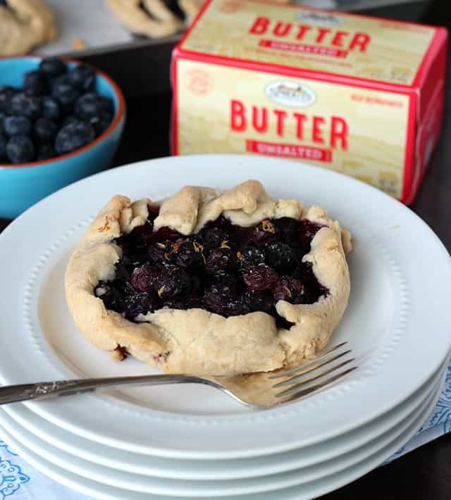 Gluten-free Blueberry Galette on plate, bowl of blueberries and carton of butter