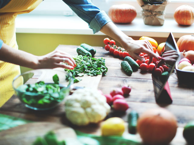 Woman preparing a salad with assorted veggies on a table