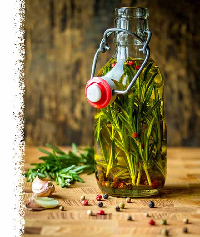 Olive oil bottle filled with rosemary, garlic and pepper to make the perfect brine