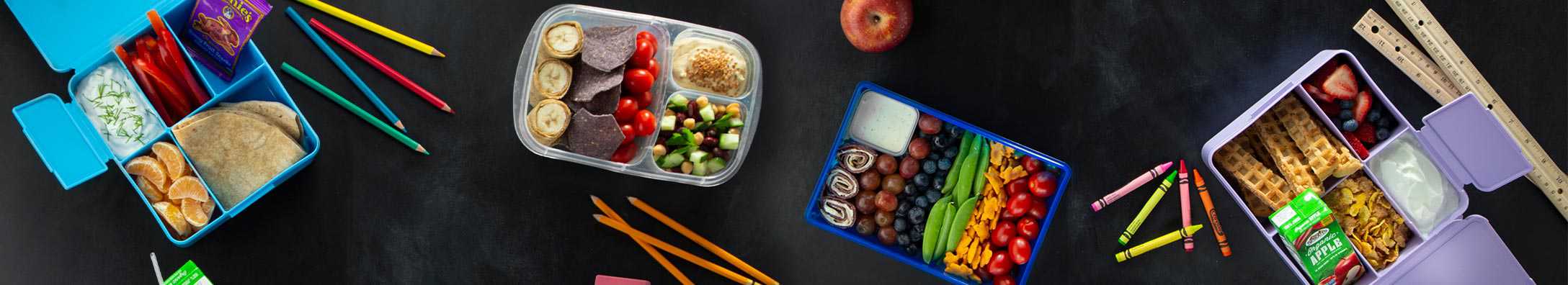 lunch boxes around school supplies on a slate background
