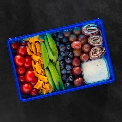 rainbow colored fruits and vegetables in a blue bento box