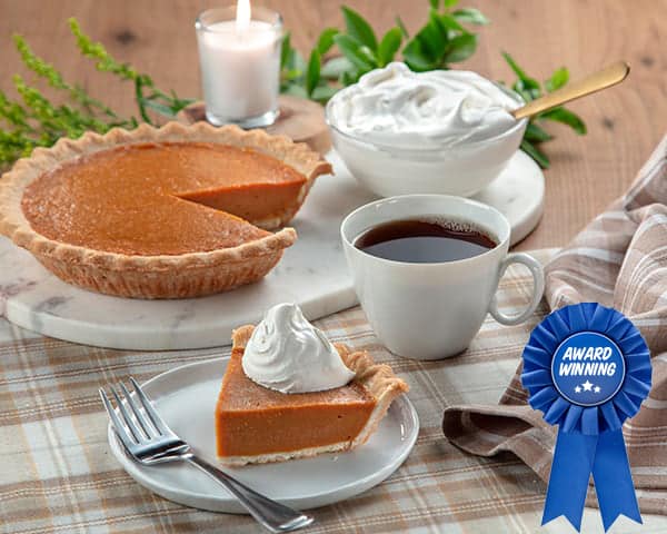 Pumpkin pie, apple pie, pecan pie, and a cup of coffee on festive table