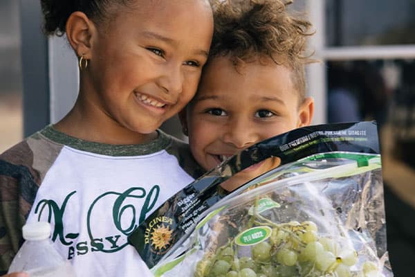 kids holding a bag of grapes