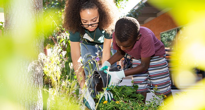 Woman helping a boy learn to garden.