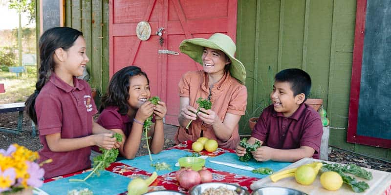 Woman teaching children around a table covered with vegetables