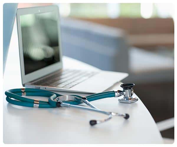 stethoscope next to medical laptop