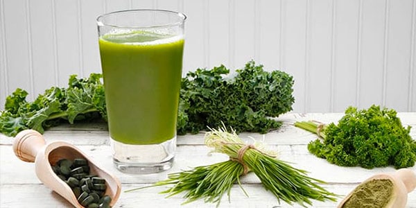 green smoothie surrounded by green vegetables