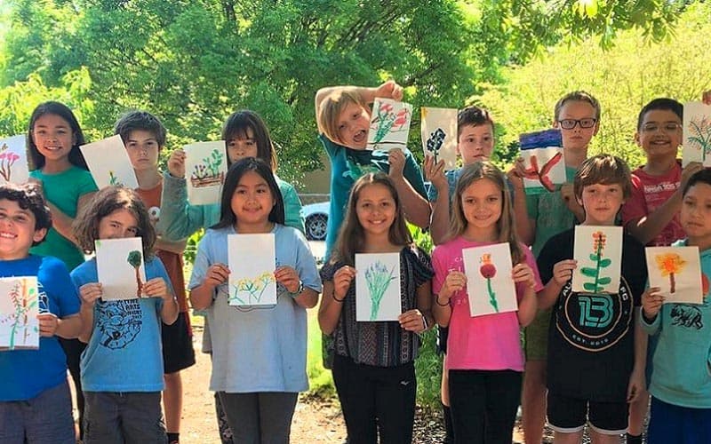 kids holding up flower drawings