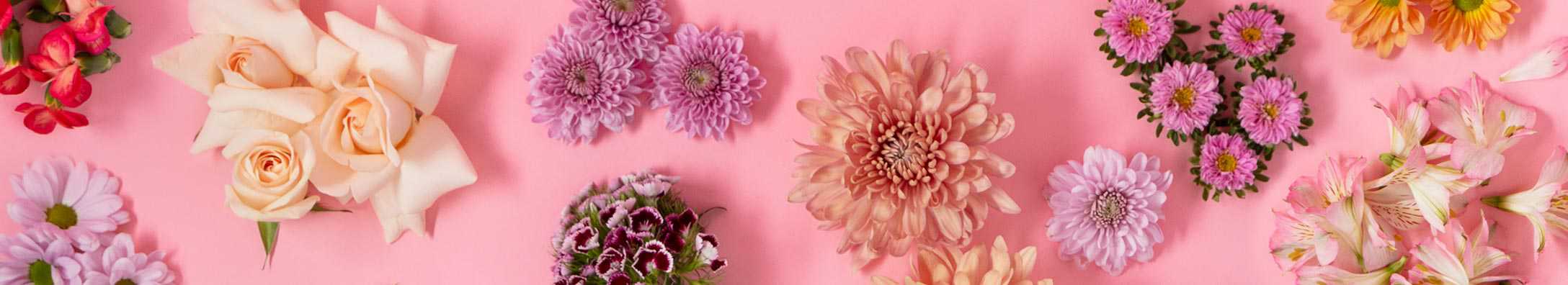 variety of flowers on a pink tabletop