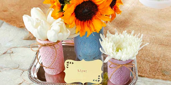 Mason jar vases holding flowers next to a card that says "mom".
