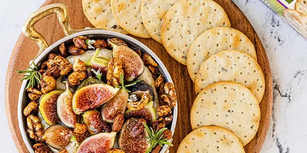Baked Brie with figs next to crackers on a serving platter