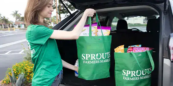 Girl loading groceries into a car.